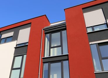 Fassadenarbeiten in Kiel. Hier an einer Fassade ein schönes Farbspiel von Beige und Rot. Ein moderner Fassadenanstrich